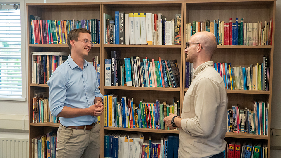 Simon Quince and Lewis Fogarty standing in front of a bookshelf.